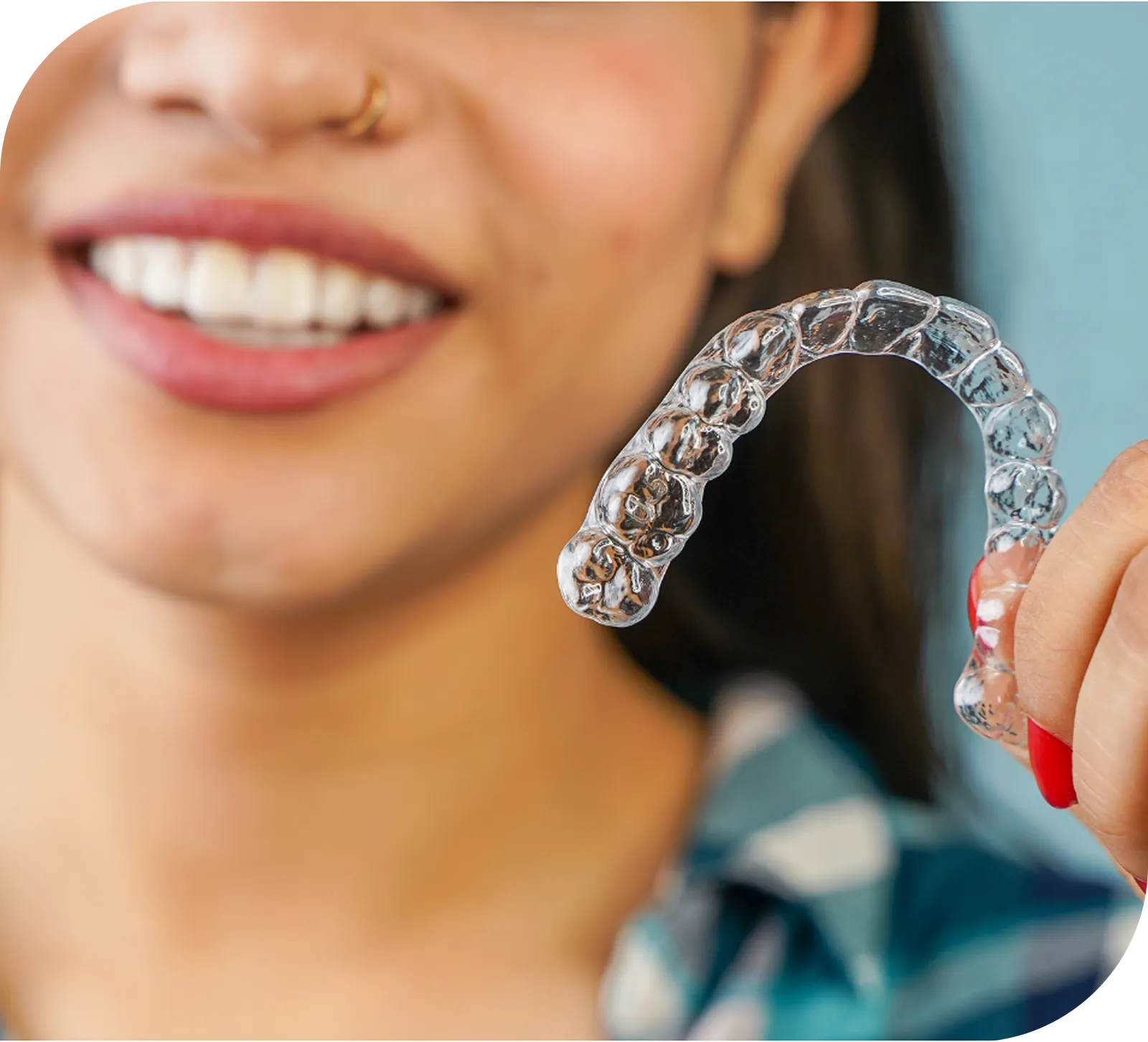 Smiling woman holding a clear invisible aligner