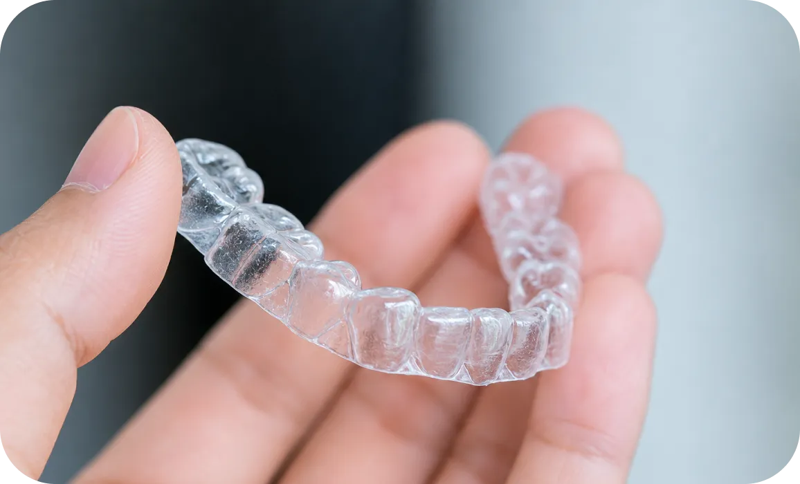 Hand holding an invisible aligner